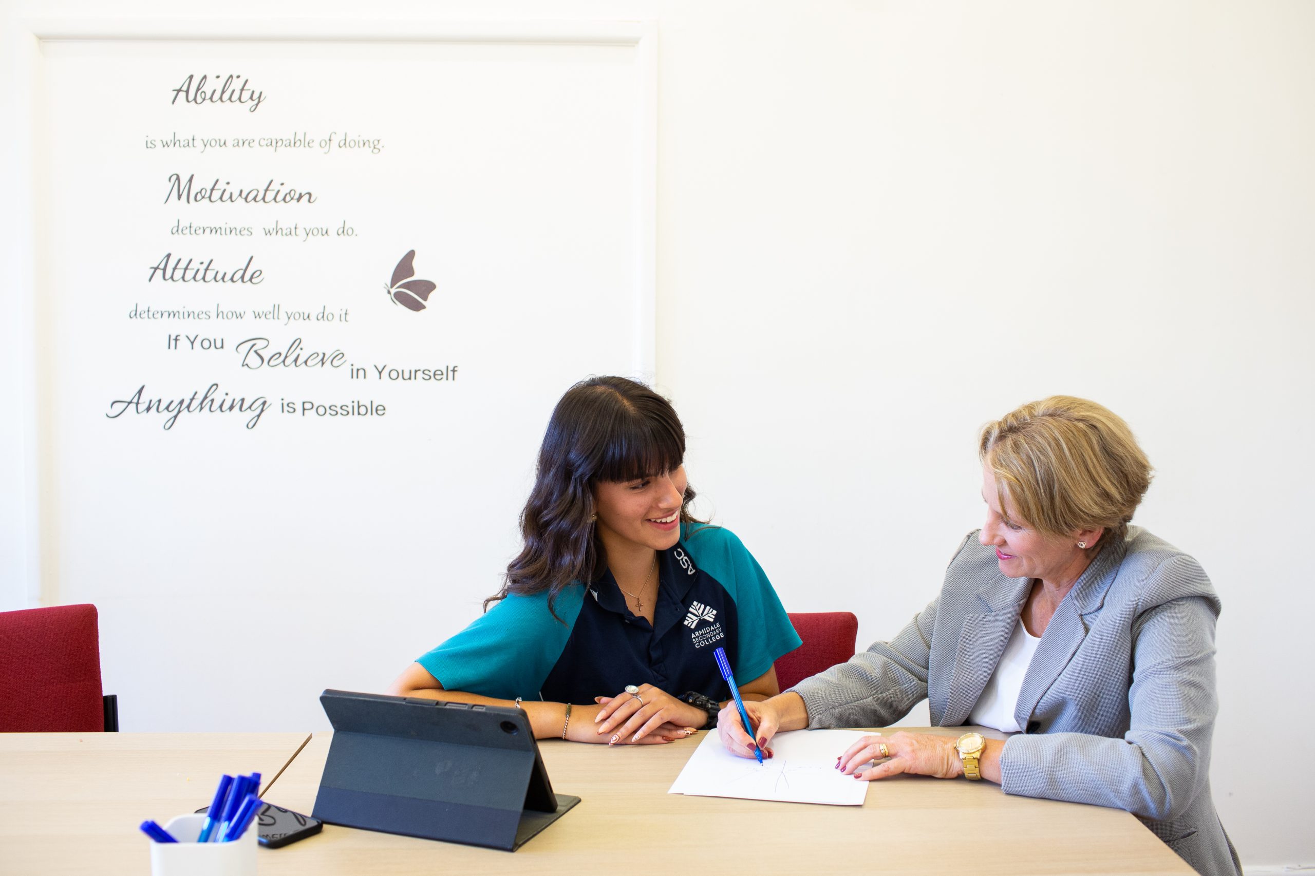 Professional woman and teenage girl at desk smiling